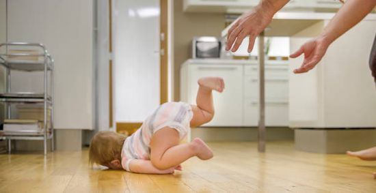 Baby boy falling on wooden floor.
