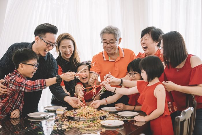 an asian chinese family celebrating chinese new year's eve with traditional food Lou sang (raw fish dishes) during reunion dinner