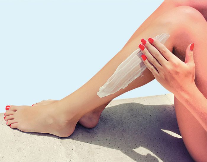 Woman apply cream on her smooth tanned legs